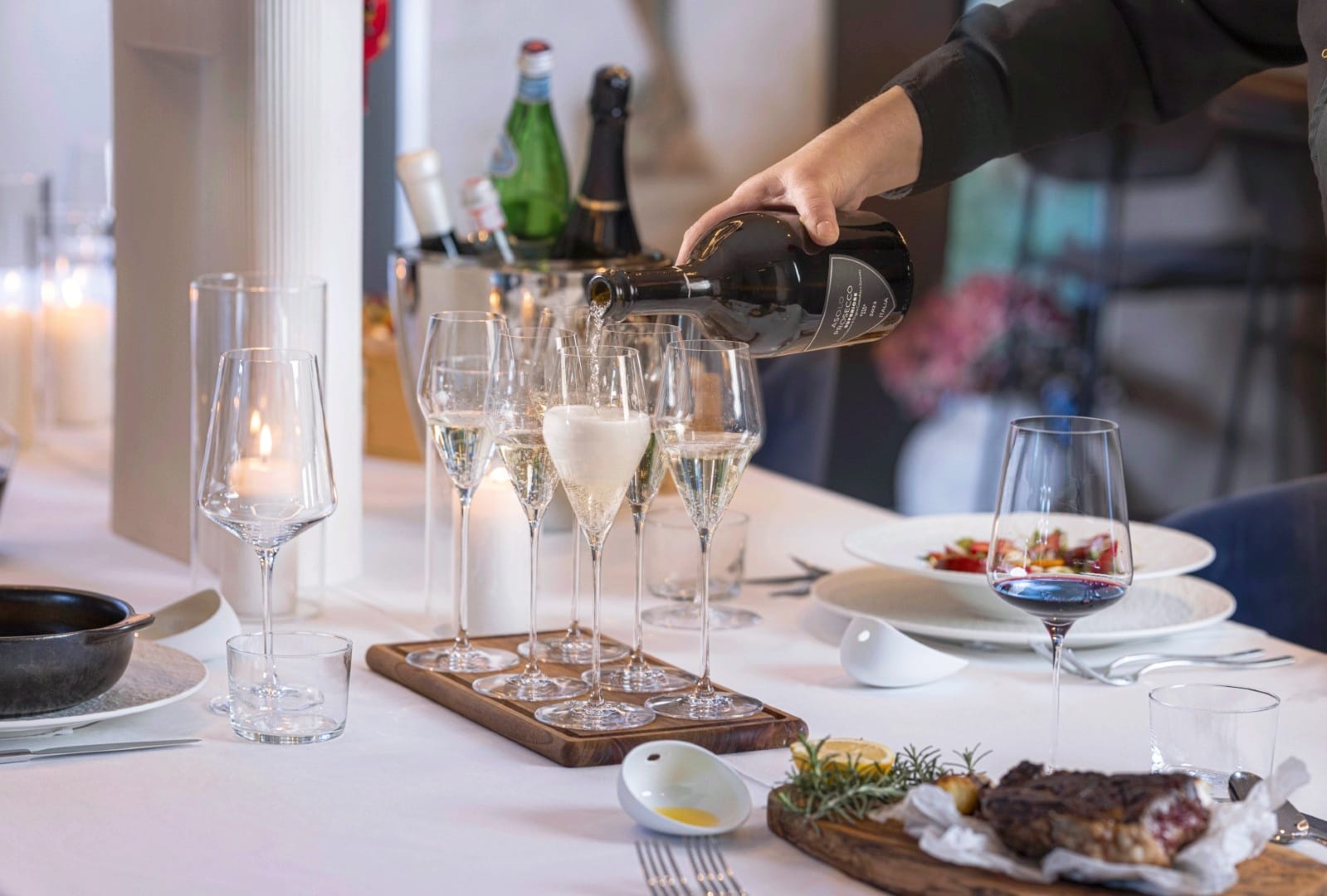 Private chef service pouring sparkling wine at a villa dinner table with grilled steak and seasonal dishes near Dubrovnik