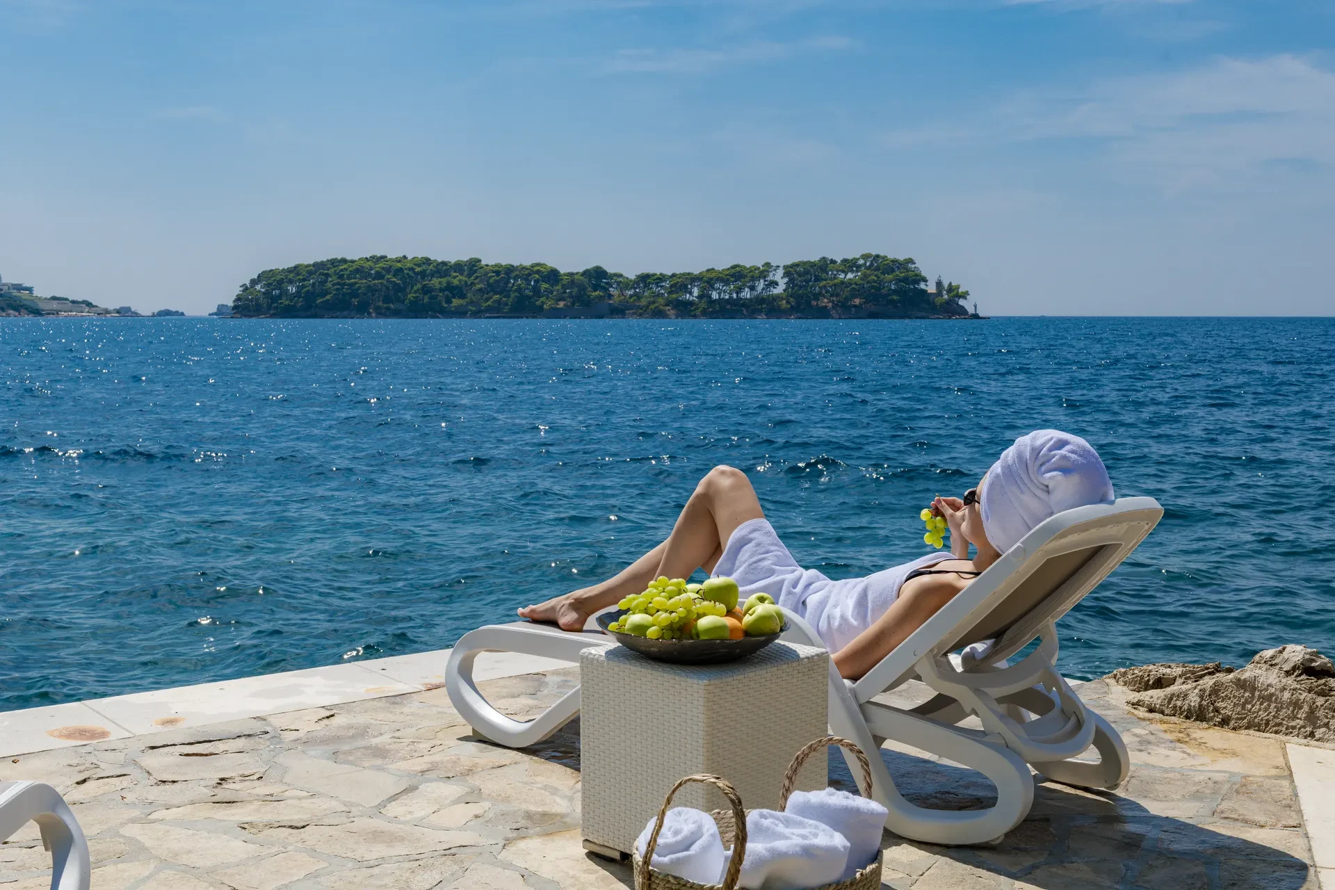 Guest relaxing on a sun lounger with direct sea access and a view of Lokrum Island at Villa Dubrovnik Cardinale