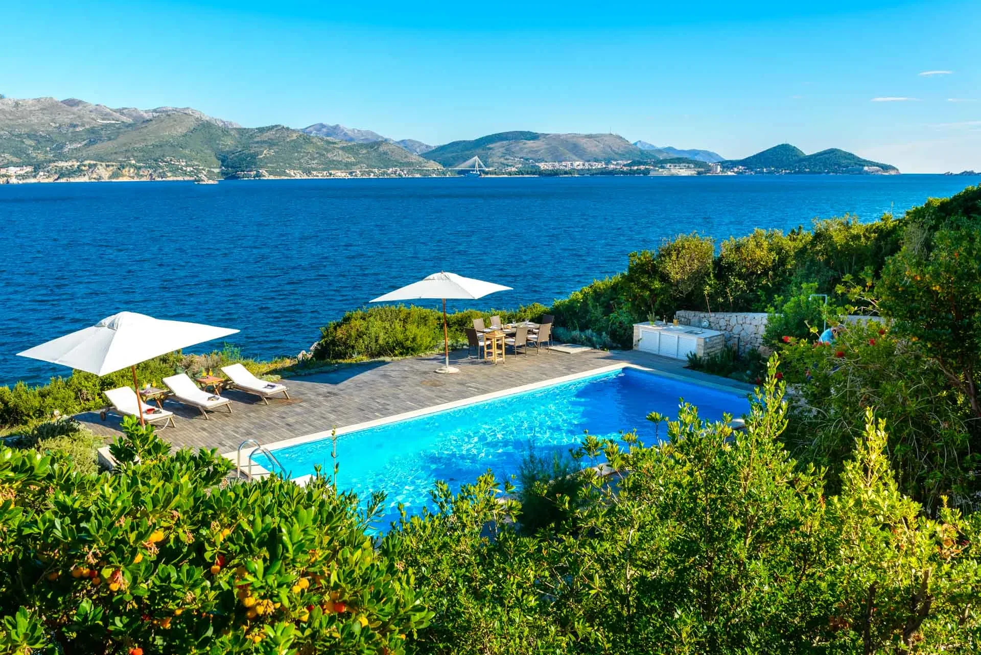 Private outdoor pool with sun loungers in front of the luxury holiday villa Calamota with a private sea deck right by the sea