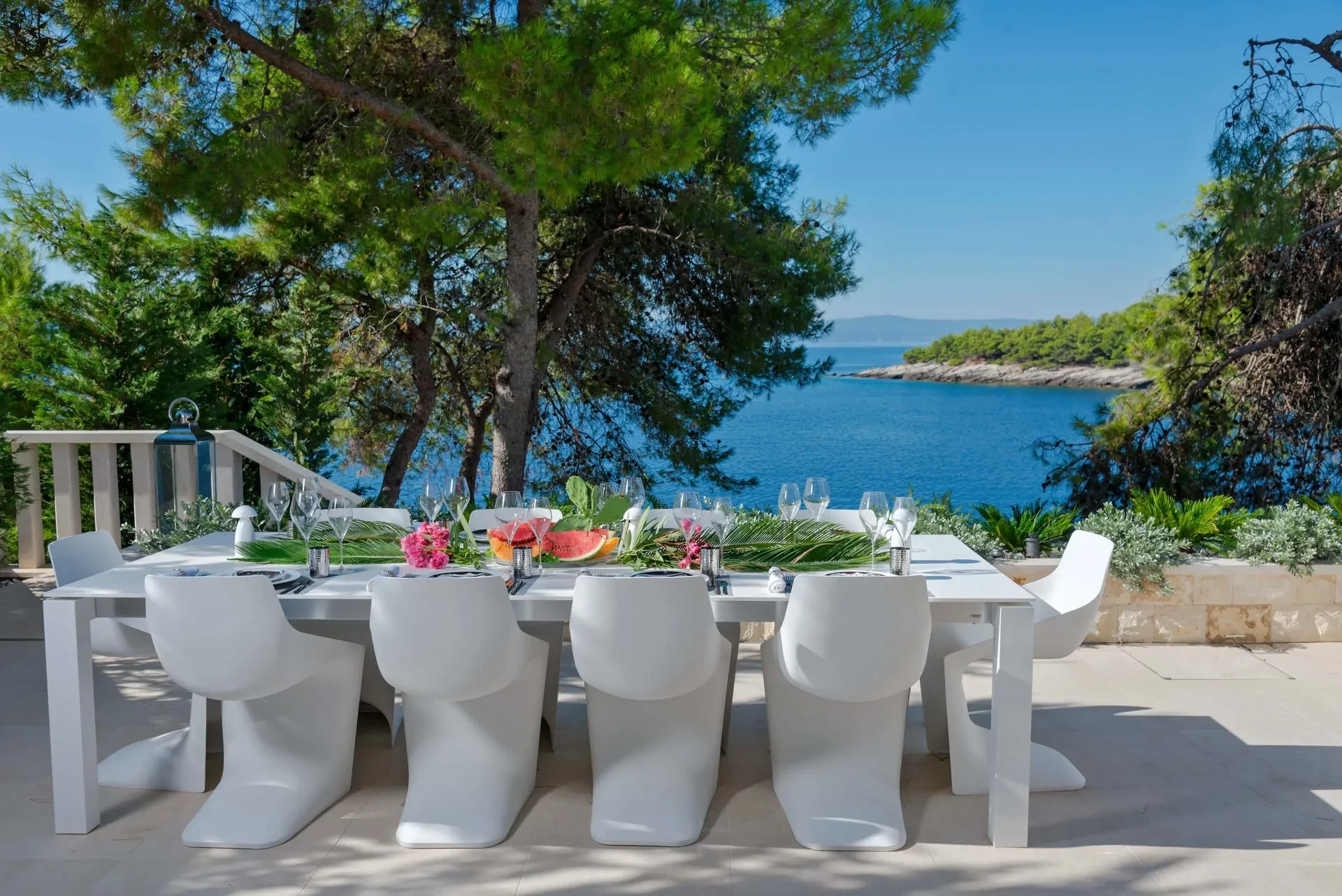 A beautifully set dinner table on the terrace of seaside Villa Acoona, overlooking an island view at sunset.