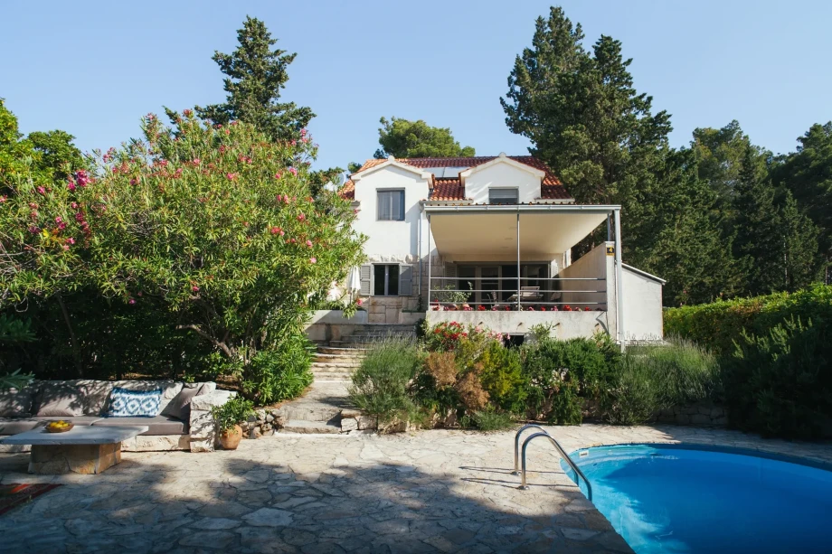 Seafront Villa Bol Retreat on Brac with a pool and patio, surrounded with Mediterranean plants.