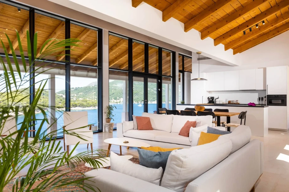 Spacious living room of the luxury villa, My Place, featuring a kitchen at the bottom of the room and an open view of the sea.