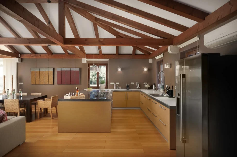 A spacious kitchen with high-quality appliances and a large dining room featuring comfortable chairs around a beautiful, large dining table in a luxurious villa in Istria