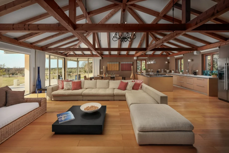 Spacious living room at Rubini Estate in Rovinj, featuring wooden beams and a large, comfortable couch.