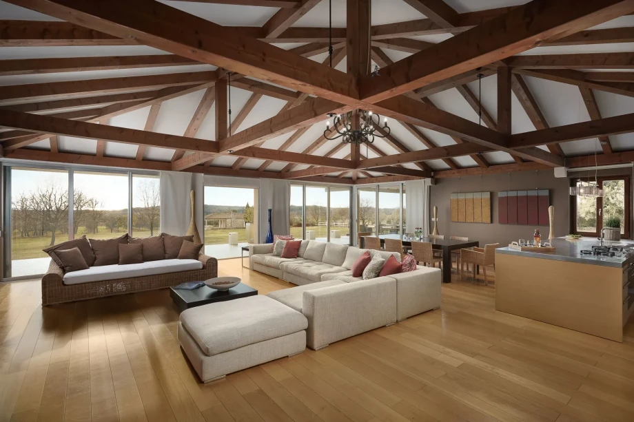 Spacious living room at Rubini Estate in Rovinj, featuring wooden beams and a large window for natural light.