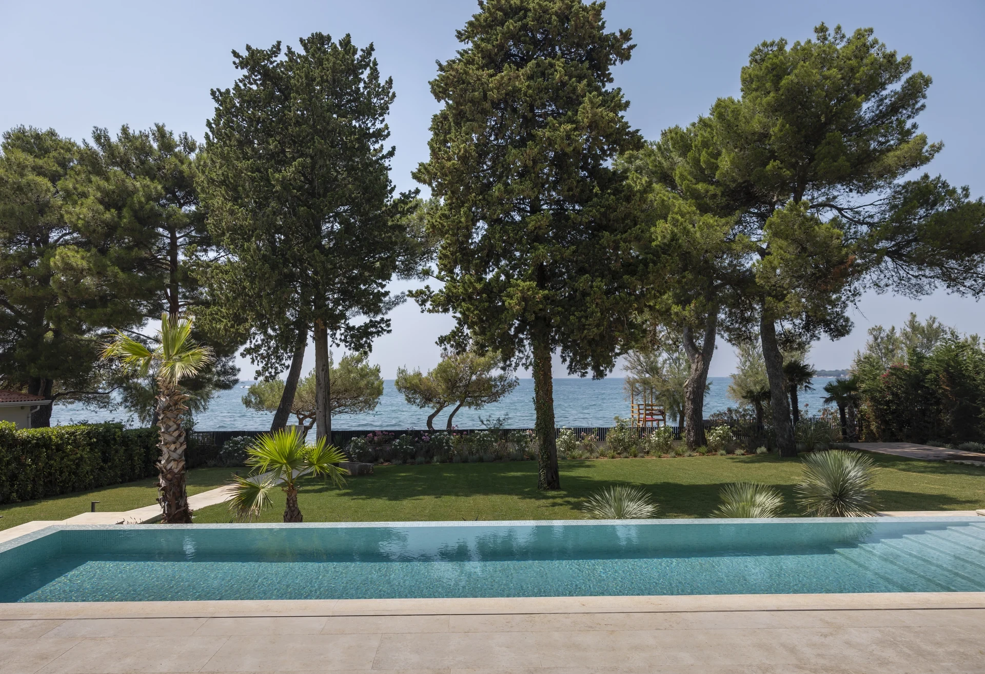 Beautiful swimming pool by the sea, by lush trees and the sea, reflecting the idyllic atmosphere of Poreč, Croatia.