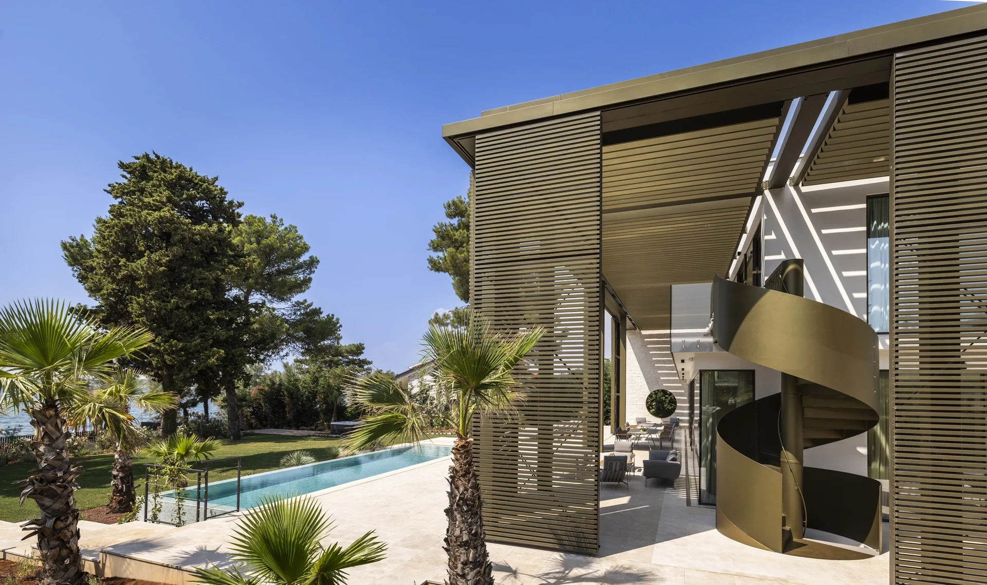 Discover the elegance of Villa Lani in Poreč, featuring a modern spiral staircase and beautiful palm trees for a serene retreat.