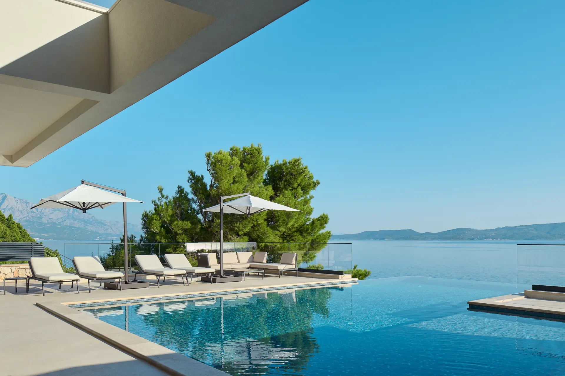 Private heated infinity pool with sun loungers and sun shades in luxury private villa with sea view