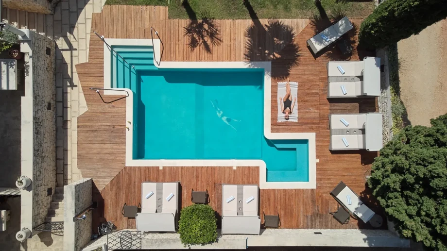 Aerial view of Villa Priska's swimming pool and deck, highlighting the clear water and sun loungers around the pool.