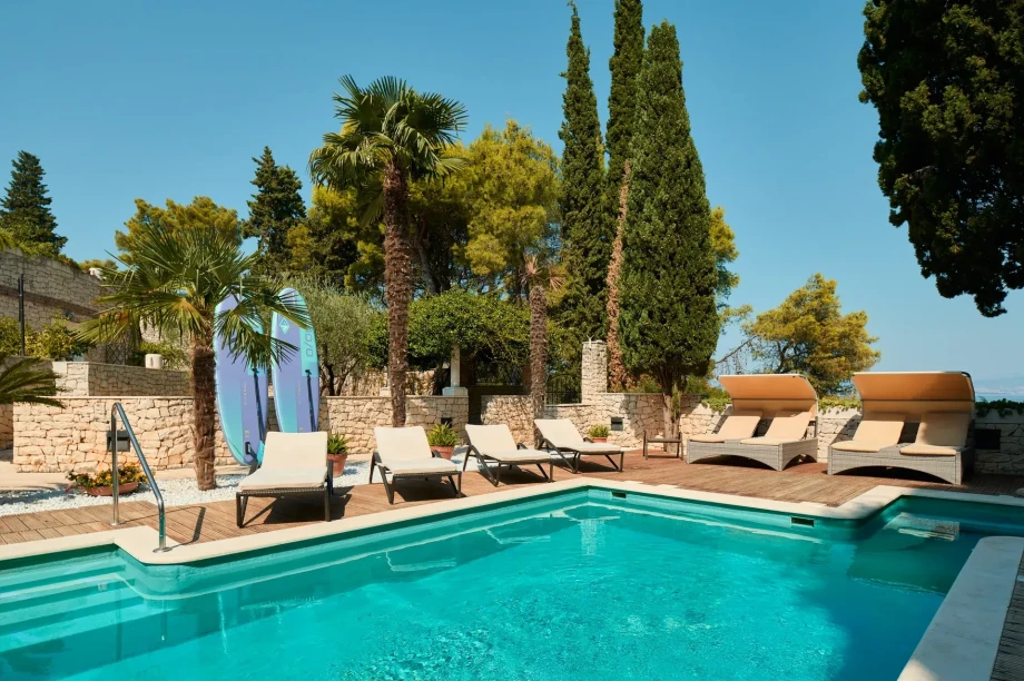 The inviting pool area at Villa Priska features lounge chairs and umbrellas for sunbathing and shade.