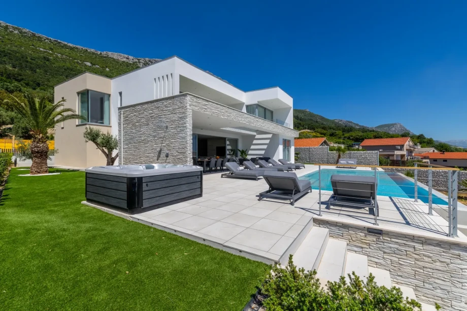 Modern Villa Nikita featuring a swimming pool and a spacious terrace surrounded by lush greenery.