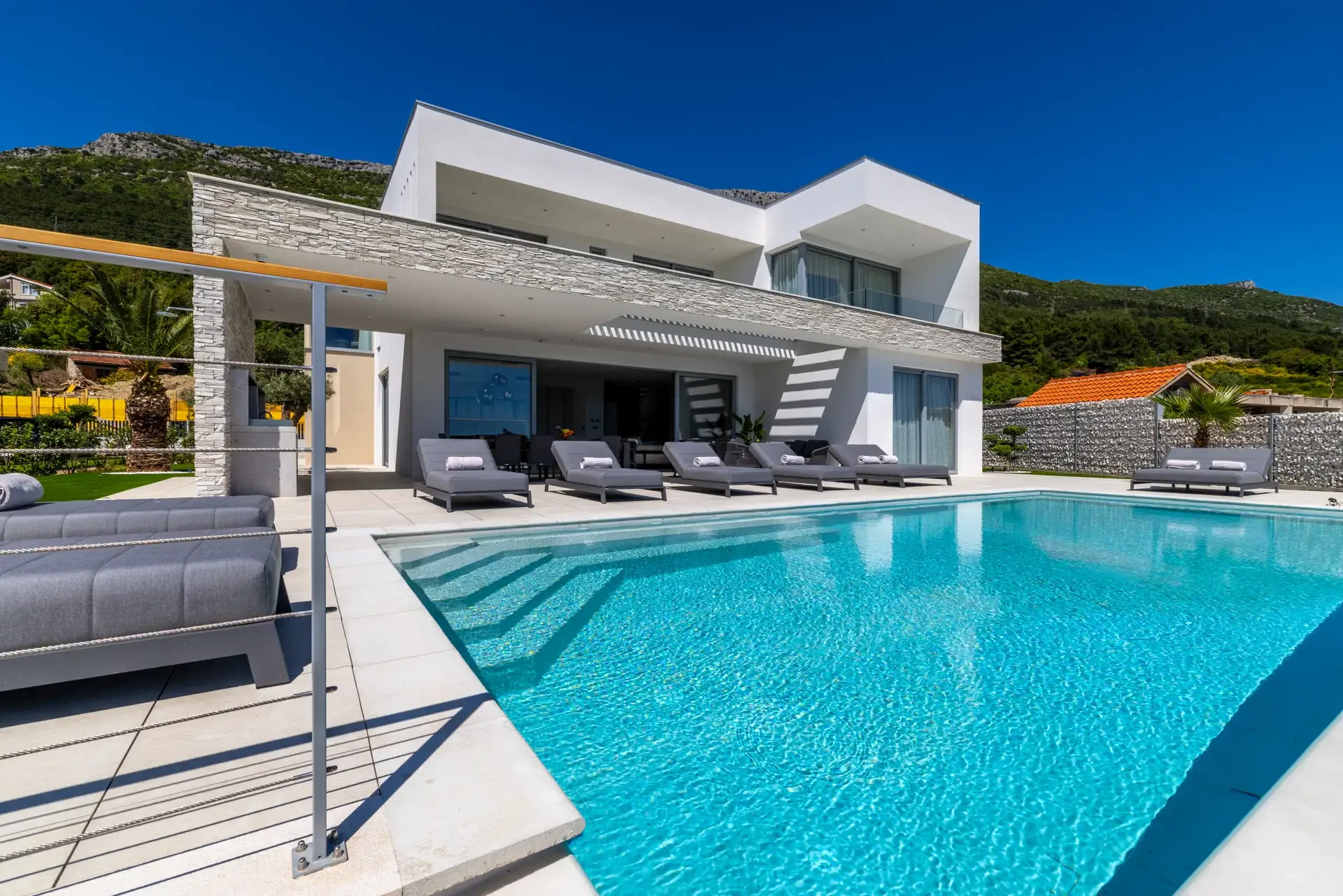 Modern Villa Nikita in Croatia featuring a sleek design and a big swimming pool surrounded by loungers.