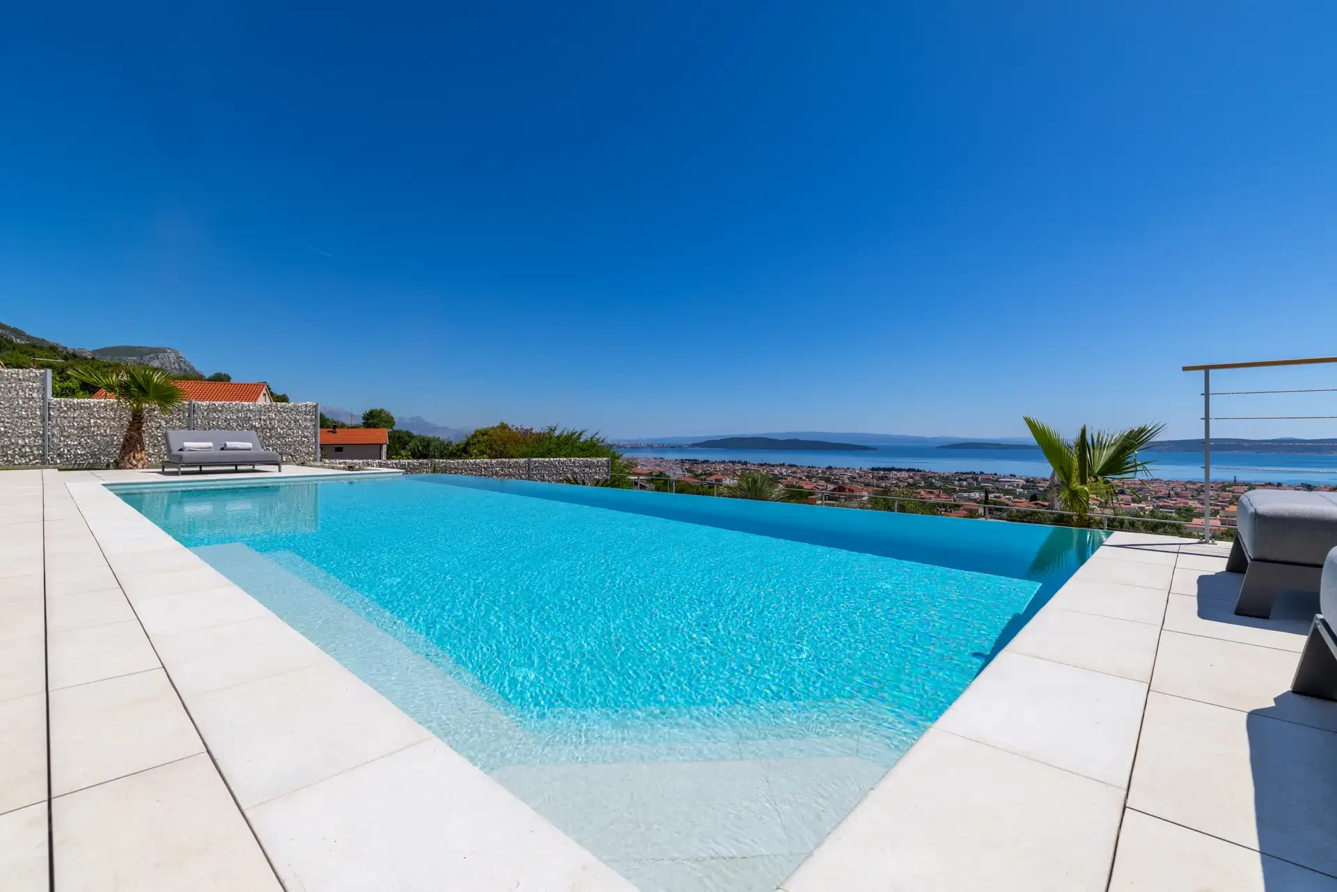 A large swimming pool at Villa Nikita, surrounded by a scenic view of the land and sea,