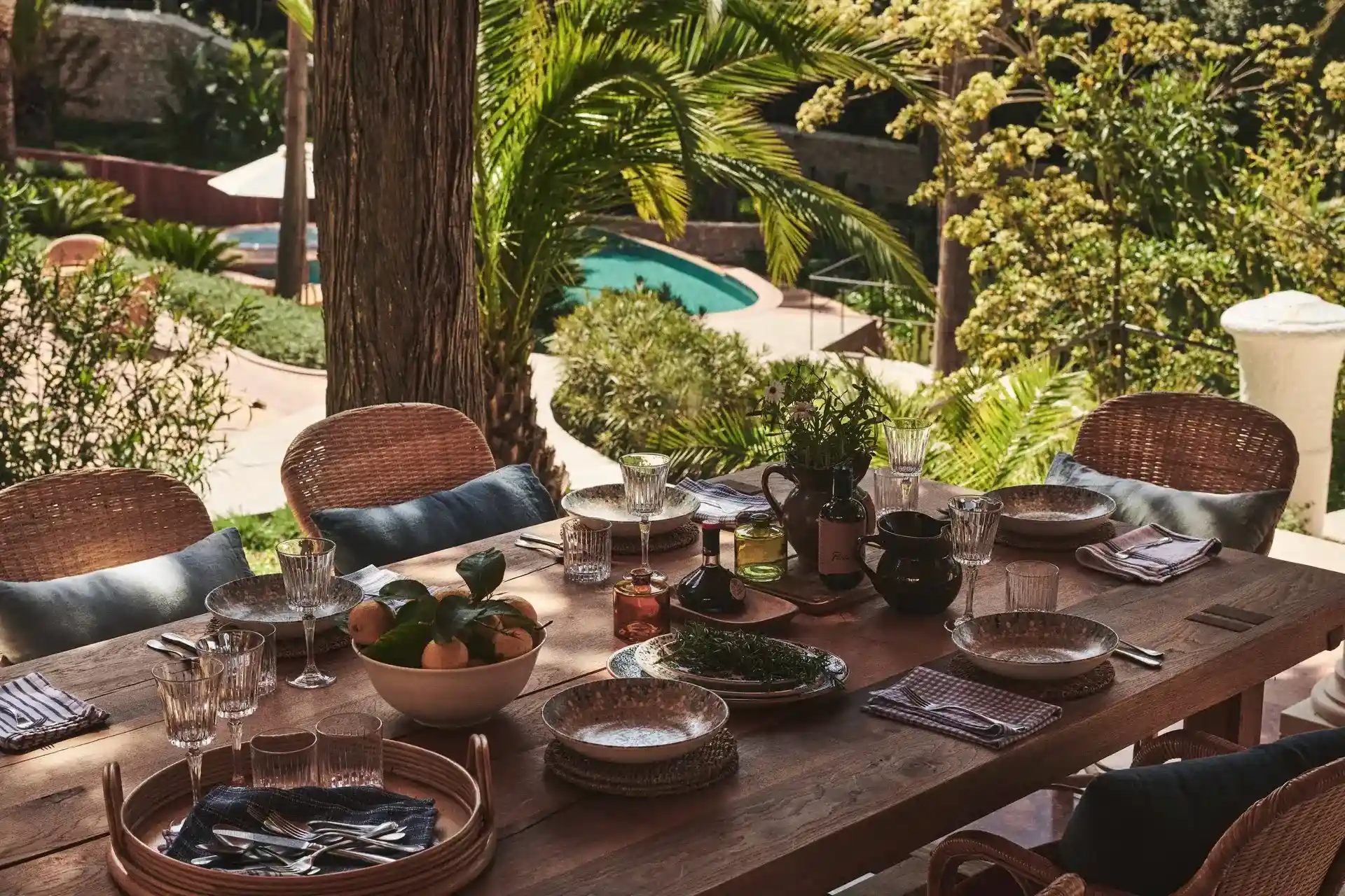 Dining table and chairs situated beneath a spacious tree by the luxurious Villa Rouge.