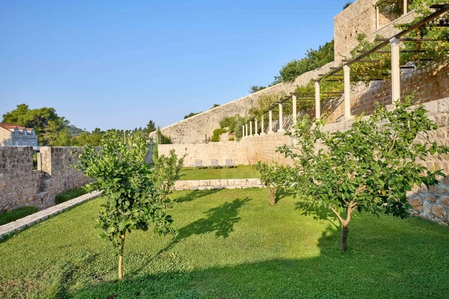 Landscaped Mediterranean garden with citrus trees and historic stone walls on island Šipan near Dubrovnik