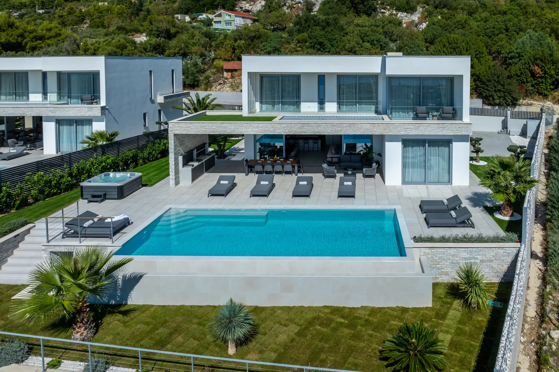 A modern villa featuring a swimming pool and expansive green lawn, showing contemporary architecture and outdoor space.