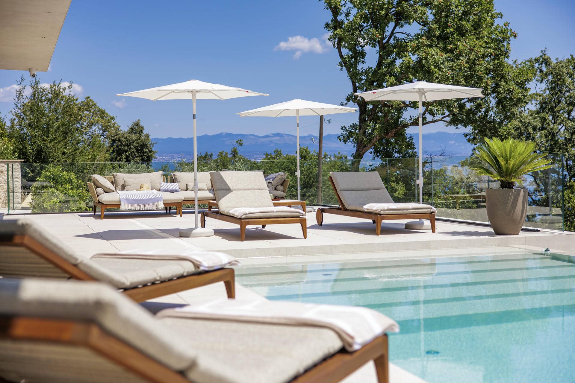 A serene poolside scene featuring lounge chairs and umbrellas, perfect for relaxation at a Croatian holiday home.