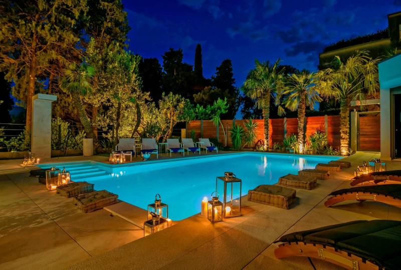 A serene night view of a pool surrounded by softly glowing candles at Villa Nobile, creating a tranquil atmosphere