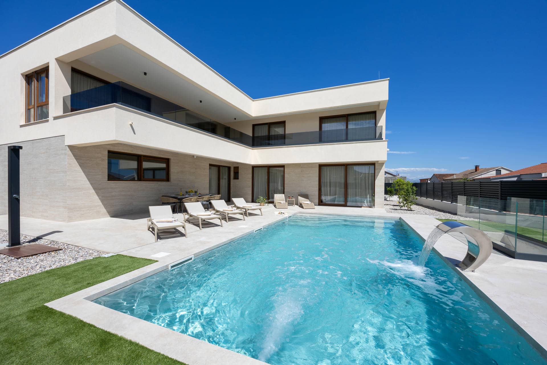Modern exterior of Villa Aria in Kaštela featuring a private swimming pool with massage waterfall, sun deck, and lush garden.