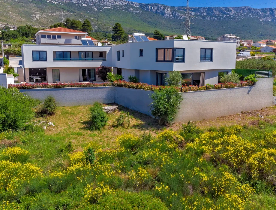 Modern exterior of Villa Adria surrounded by Mediterranean greenery and Kozjak mountain views.