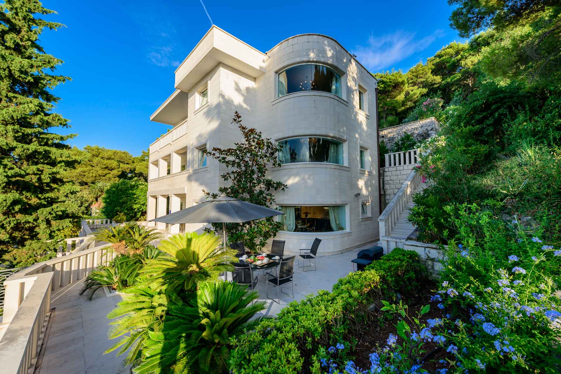 Villa Royal Dubrovnik features a spacious white house with a charming patio and a well-maintained garden.