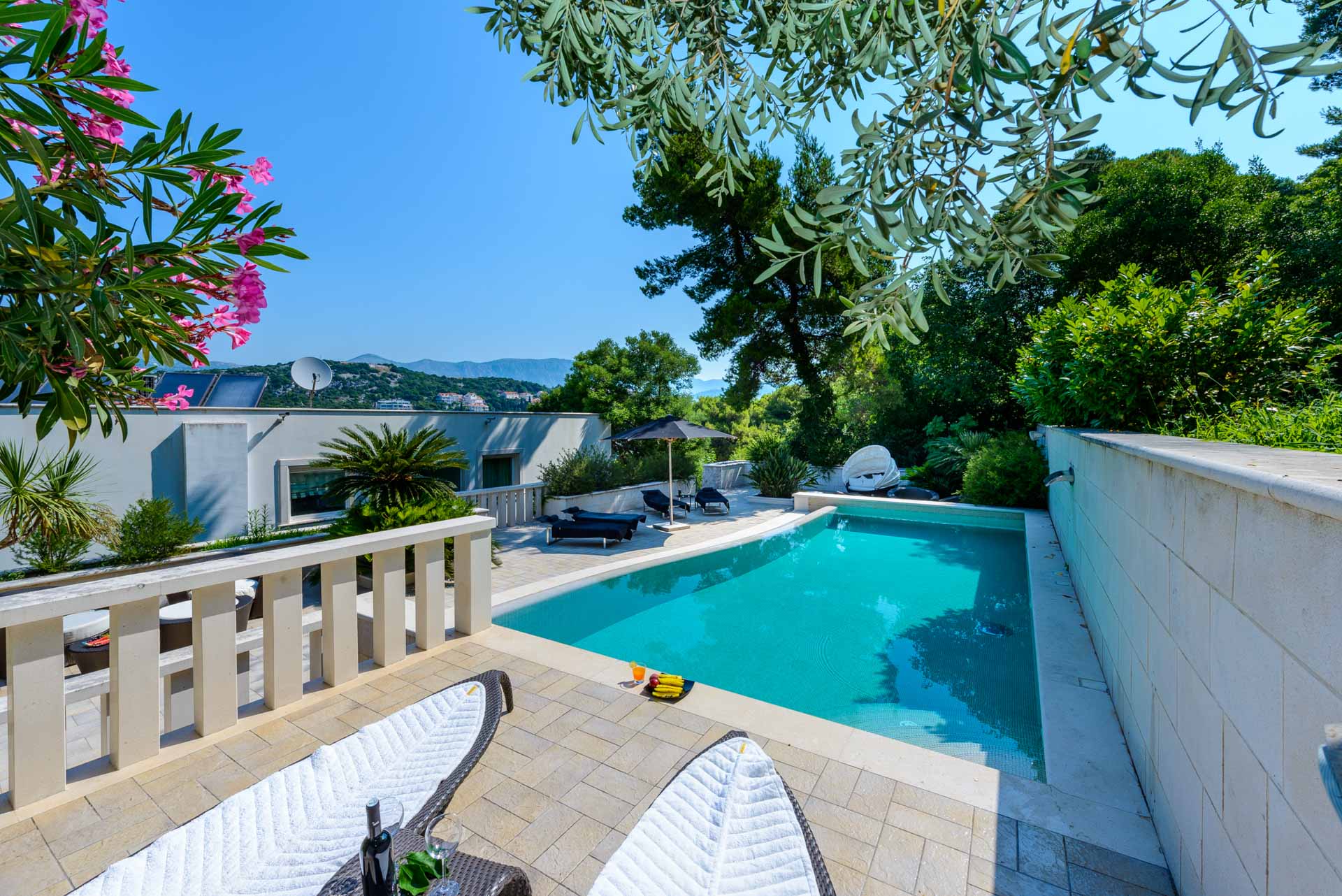 A pool with lounge chairs in front of Villa Royal Dubrovnik and relaxing outdoor space.