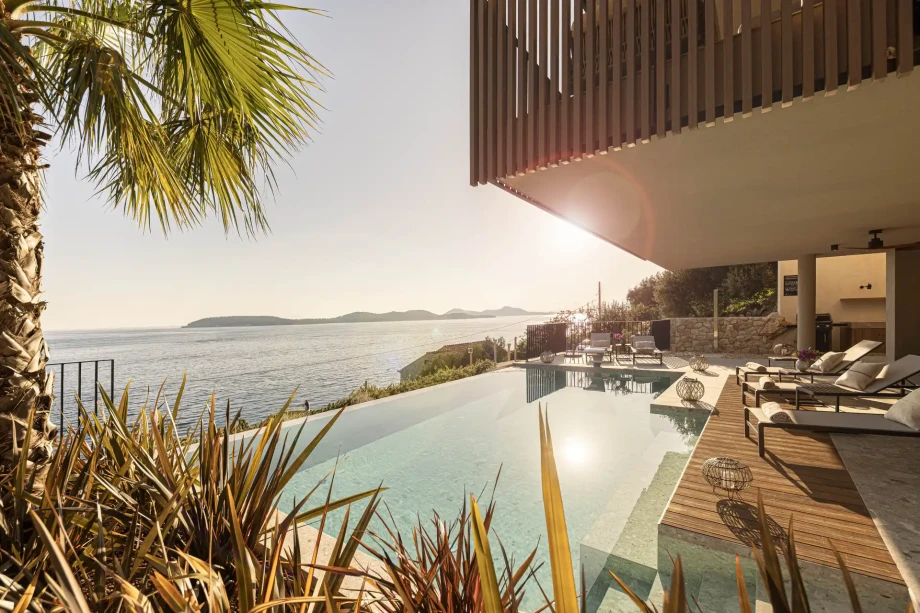 Infinity pool terrace with palm trees and sun loungers.
