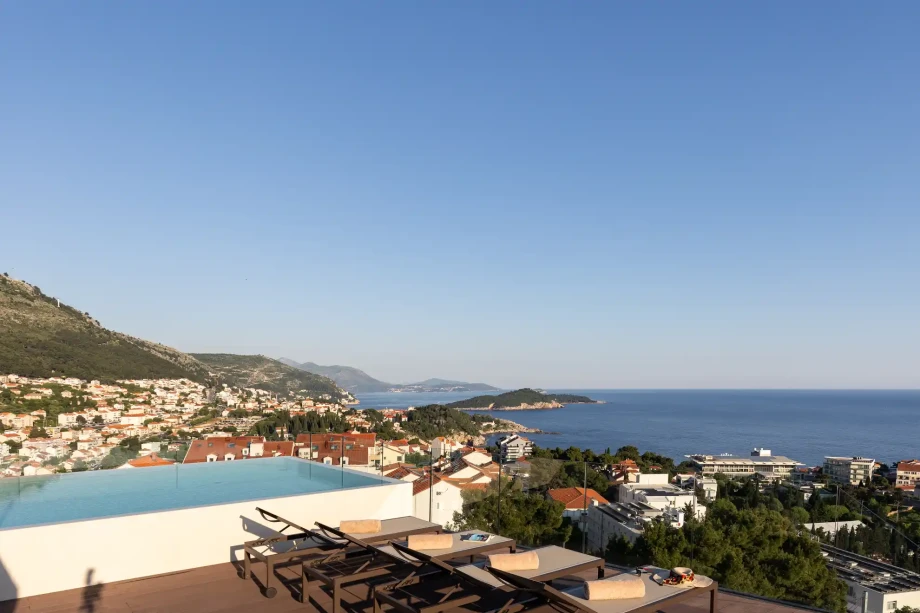 Rooftop infinity pool and sun loungers with panoramic views.