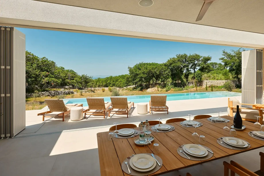 Poolside dining table at Villa Sunset Novalja on the island of Pag, overlooking the Mediterranean garden.
