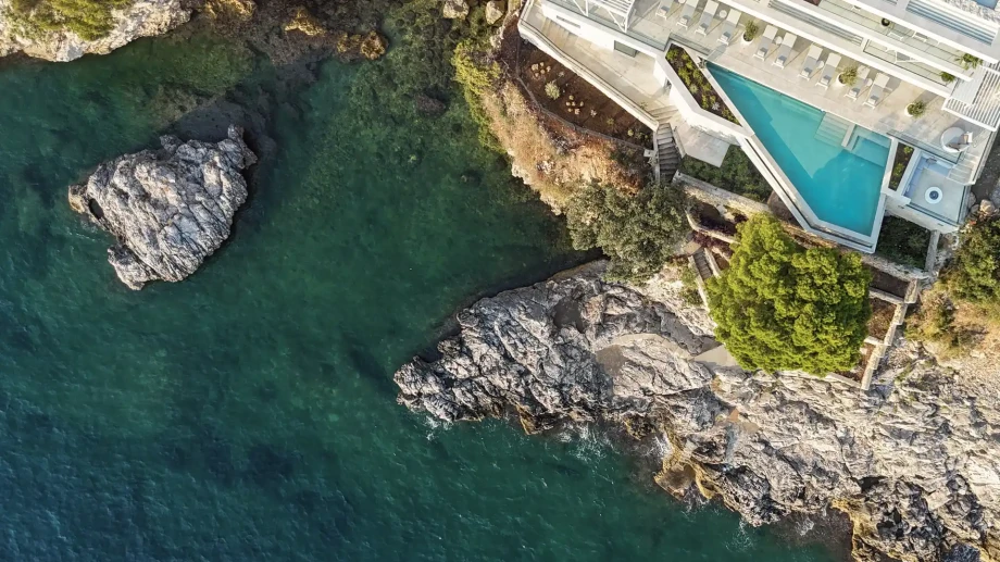 Aerial view of the infinity pool and rocky shoreline below Villa Azurea Dubrovnik.