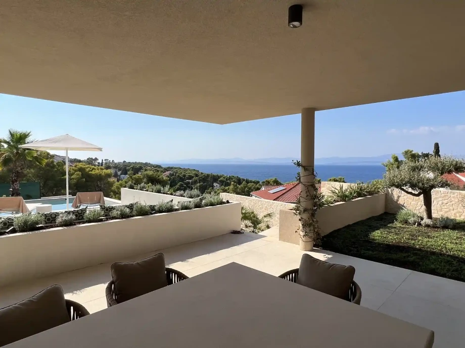 Covered terrace with outdoor dining area overlooking the private pool with sun loungers.