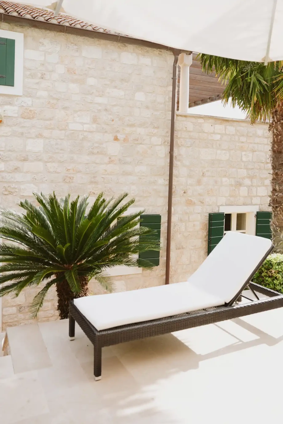 Private sun terrace with lounger surrounded by greenery.