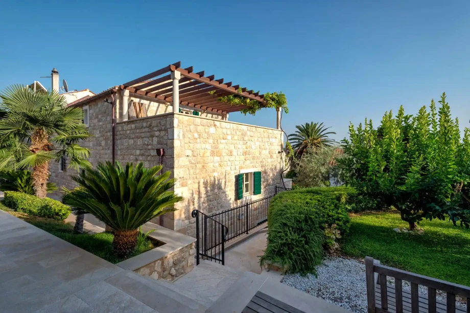 Traditional stone house with pergola surrounded by a lush Mediterranean garden in Hvar.