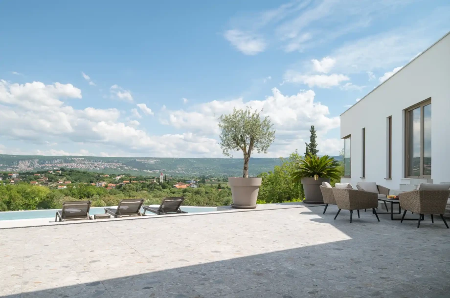 Spacious terrace beside the pool with outdoor seating and wide views across the green hills and settlements surrounding the Imotski area