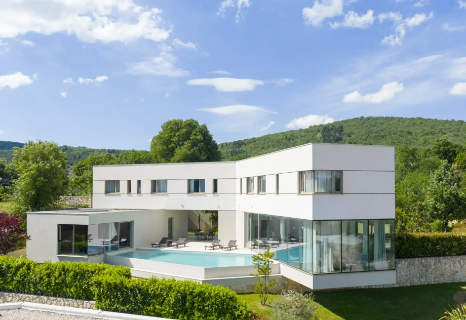 Modern exterior of Villa Imota Ruby with large glass walls, private swimming pool and contemporary architecture framed by the surrounding green landscape